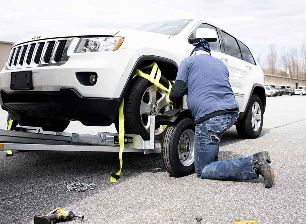 Technician securing vehicle with professional straps for safe towing in Babylon, NY